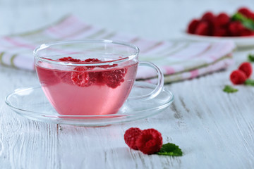 Cup of raspberry drink with berries on wooden table close up