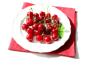 Sweet cherries on plate, on light background