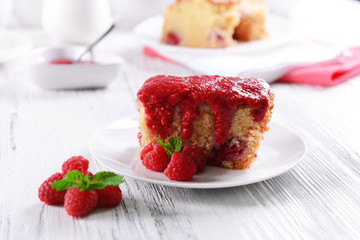 Fresh pie with raspberry jam in white saucer on wooden table, closeup