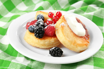 Fritters of cottage cheese with berries in plate, closeup