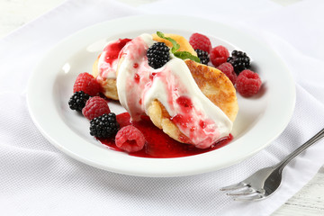 Fritters of cottage cheese with berries in plate, closeup