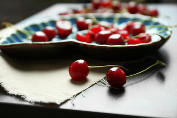 Sweet cherries on plate, on dark background