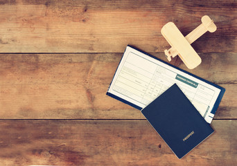 image of flying ticket wooden airplane and passport over wooden table. retro filtered image
