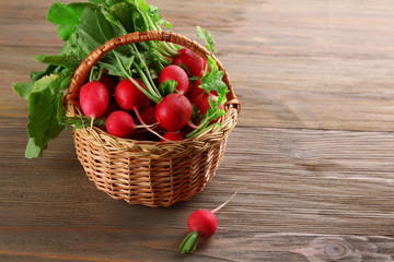 Fototapeta na wymiar Fresh radishes in basket on wooden background