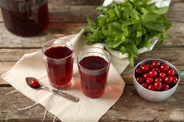Two glasses with cherry juice on table, on wooden background