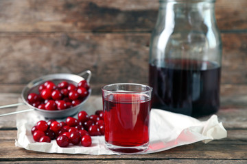 Glass with cherry juice on table, on wooden background