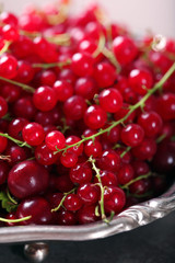 Ripe red currants in metal bowl on table, closeup