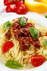 Spaghetti Bolognese on white plate, on color wooden background