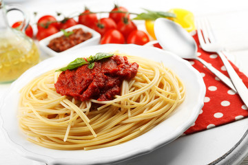 Spaghetti with tomato sauce and cheese on white plate, on color wooden background