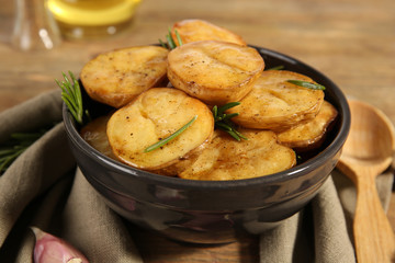 Delicious baked potato with rosemary in bowl on table close up