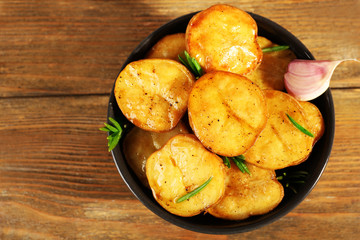Delicious baked potato with rosemary in bowl on table close up