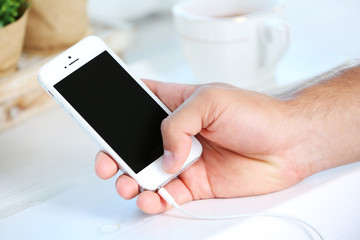 Music smartphone in male hand, on light background