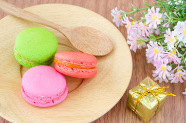 Colorful macaroons in wooden dish and flower.