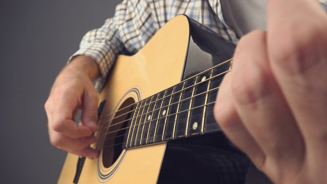 Hand picking strings on acoustic guitar, unplugged blues rock music performance, close up, 4k uhd footage