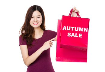 Asian woman with finger point to shopping bag and showing autumn