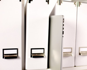 File folders, standing on  shelves in the background