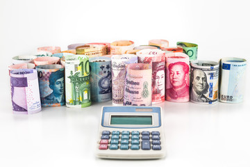 Pile of rolled-up currency notes with a calculator in foreground