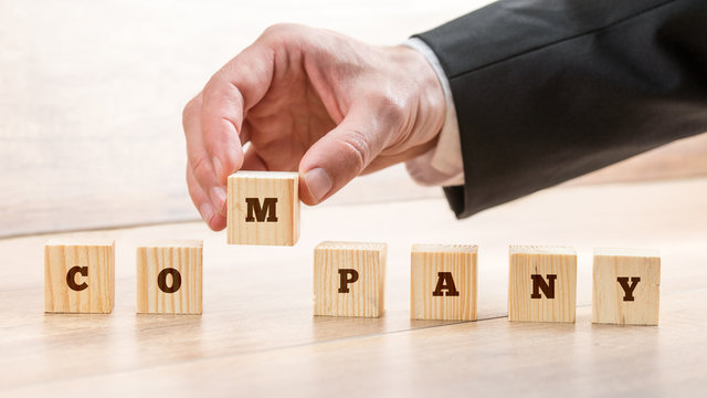 Closeup of male hand putting together word COMPANY on seven wooden cubes. Conceptual of building a competent business team to lead progressive company.
