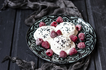 rice with black sesame ice cream and raspberries on the black board with black gauze