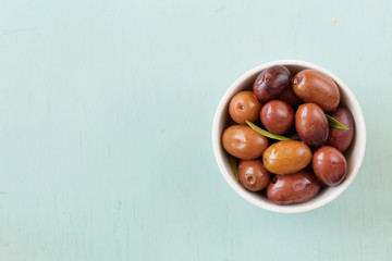 Fresh olives in white bowl on rustic wooden table