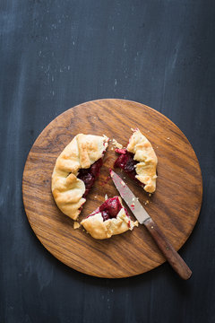 Homemade sour cherry pie on the wooden cutting board. Chalkboard background with copy space