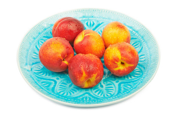 Ripe nectarines with water drops in a wicker plate