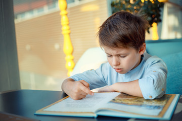 Boring and tired little boy reading book