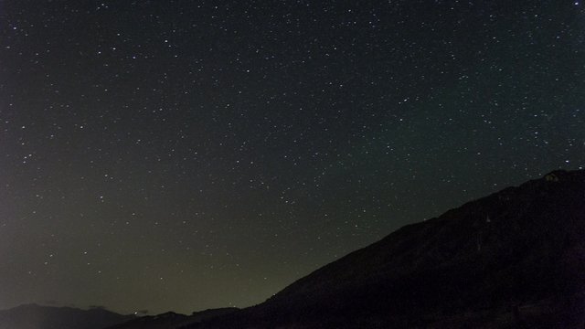 stars moving in night sky over mountain ridge
