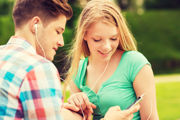 smiling couple with smartphone and earphones