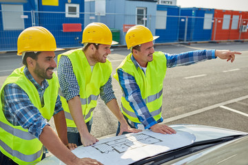 close up of builders with blueprint on car hood