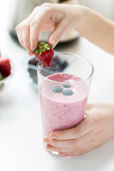 close up of woman with milkshake and strawberry