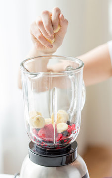close up of woman hand adding fruits to blender