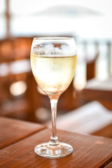 Glas of cold white wine on a wooden table.
