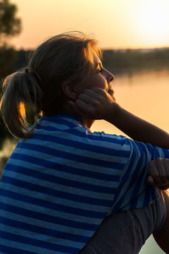 Женщина на берегу озера на закате