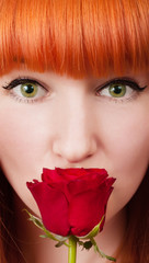 Red-haired woman with a rose on her mouth