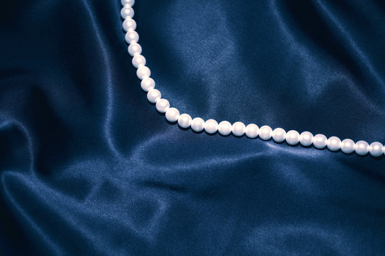 white pearl necklace on a dark blue silk