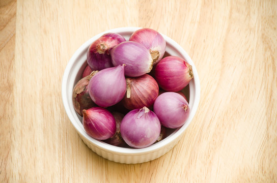 Fresh shallots in the bowl on wooden background