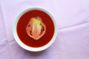 Tomato soup, made of ripe tomato, onion, salt and sugar and decorated with slice of raw oxheart tomato 