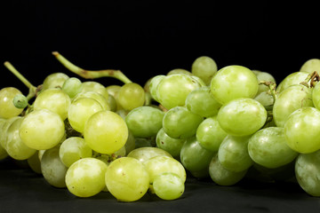 White and green table grapes on black background