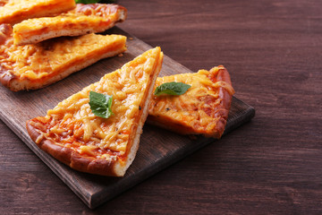 Slices of tasty cheese pizza with basil on table close up