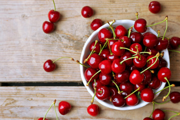 Sweet cherries in bowl on wooden table close up