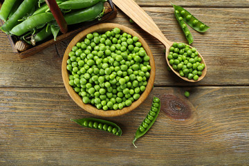 Fresh green peas in bowl and spoon on table close up