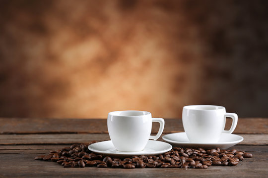 Cups of coffee and beans on blurred background © Africa Studio