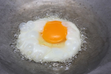 cooking fried egg in hot pan with oil