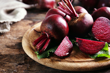 Young beets with leaves on wooden table close up
