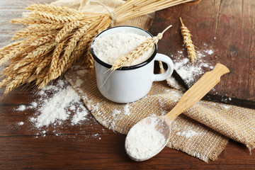 Whole flour with wheat on wooden table, closeup