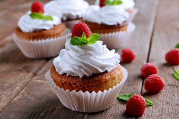 Delicious cupcakes with berries and fresh mint on wooden table close up