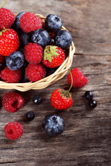 Sweet tasty berries in basket on wooden table close up