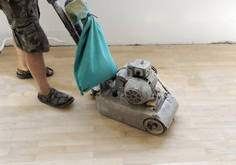 Worker sanded oak wooden floor with professional machine