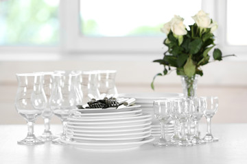 Clean plates, glasses and cutlery on white table